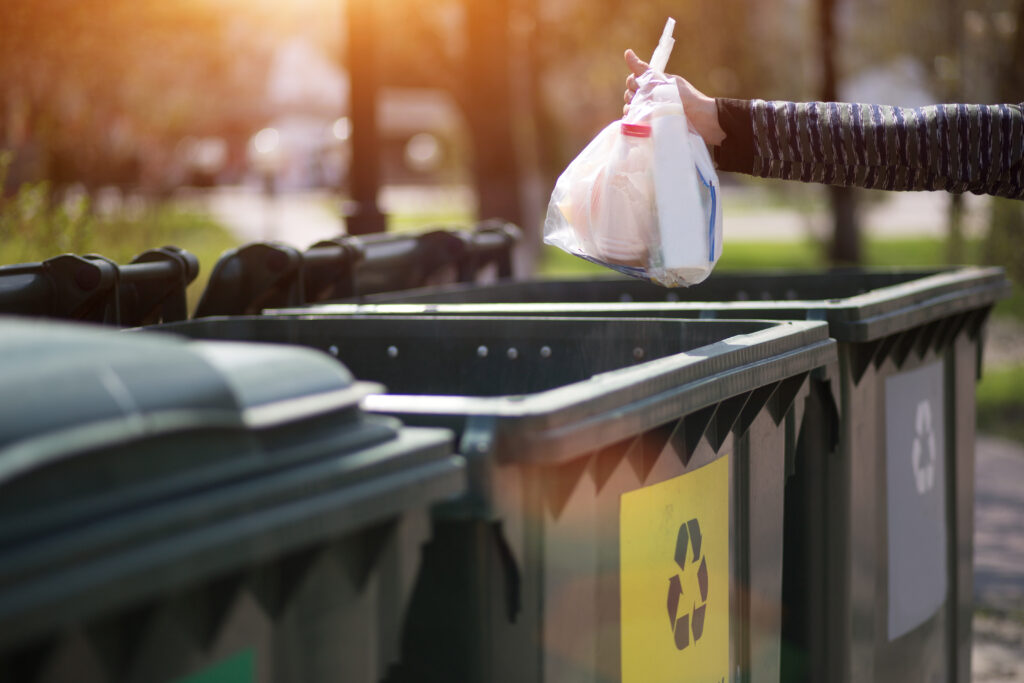 Hand with a bag of plastic garbage over containers for separatio