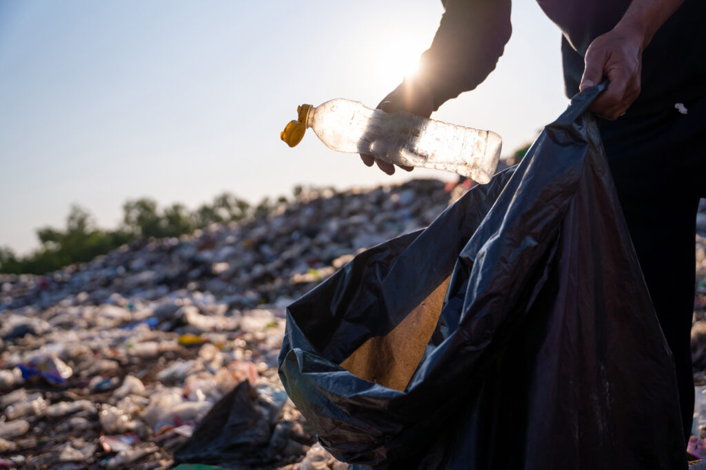 Close up hand collecting plastic bottle garbage for recycling co